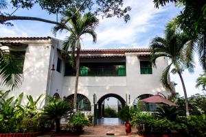 a white building with palm trees in front of it at Sotovocce Casa Campestre in Turbaco