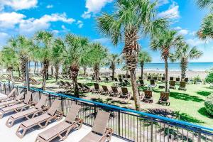 a row of chaise lounge chairs on a balcony with palm trees at Stunning View, Direct Oceanfront, Boardwalk, Pools in Myrtle Beach