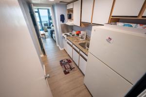 a small kitchen with a refrigerator and a sink at Stunning View, Direct Oceanfront, Boardwalk, Pools in Myrtle Beach