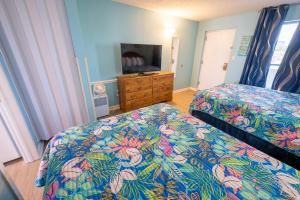 a bedroom with two beds and a dresser and a mirror at Stunning View, Direct Oceanfront, Boardwalk, Pools in Myrtle Beach +14 photos