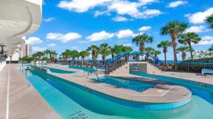 a pool with a slide at the beach with palm trees at Stunning View, Direct Oceanfront, Boardwalk, Pools in Myrtle Beach