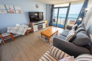 a living room with a couch and a television at Stunning View, Direct Oceanfront, Boardwalk, Pools in Myrtle Beach
