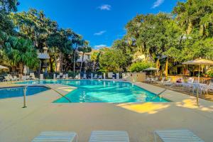 a swimming pool at a resort with chairs and trees at Springwood Villas 21 in Hilton Head Island