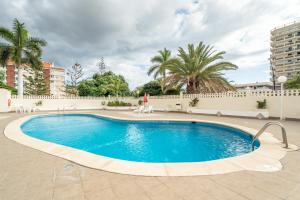 Una gran piscina en un patio con palmeras. en Las Rosas Sunset Apartment, en Arona