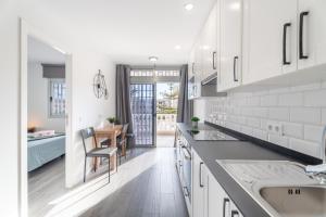 Una cocina blanca con un fregadero y una mesa. en Las Rosas Sunset Apartment, en Arona