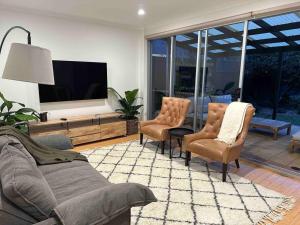 a living room with a couch and chairs and a tv at The Goody House in Unley