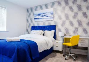 a bedroom with a blue bed and a yellow chair at Caasi Homes in Leigh