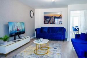 a living room with a blue couch and a tv at Caasi Homes in Leigh