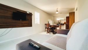 uma sala de estar com um sofá e uma televisão na parede em CASA NA RUA DO PIRUÍ EM AREMBEPE com ar em Arembepe