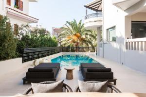 a house with a swimming pool and two lounge chairs at Sol Residence - Private Pool Gym Glyfada in Athens