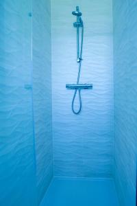 a shower with a hose in a blue bathroom at Caasi Homes in Leigh