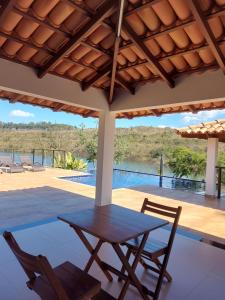 - une table et des chaises sur une terrasse avec piscine dans l'établissement Suítes Canaã, à Capitólio
