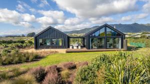 a black house on a hill with mountains in the background at Ono in Te Horo