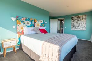 a bedroom with a large bed with blue walls at Ono in Te Horo