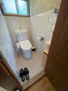 a small bathroom with a toilet and a pair of shoes at 島の宿 近 別邸〜縁〜 in Oshima