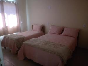 a bedroom with two beds with pink sheets and a window at Casa Beija Flor in São Thomé das Letras