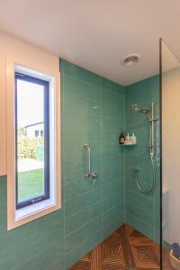 a bathroom with a shower with green tiles and a window at Ono in Te Horo
