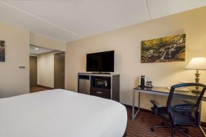 Habitación de hotel con cama, escritorio y TV. en Best Western Philadelphia South - West Deptford Inn en Thorofare