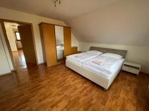 a bedroom with a white bed and a wooden floor at Dom Príbovce in Príbovce