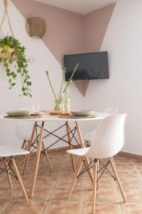 a dining room table with white chairs and a tv at La Casita del Sol in Soo