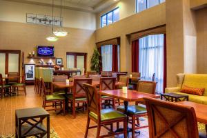 a restaurant with wooden tables and chairs and windows at Hampton Inn & Suites Mountain Home in Mountain Home