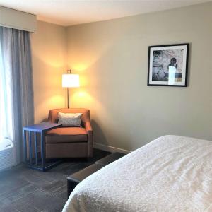 a hotel room with a bed and a chair and a lamp at Hampton Inn & Suites Norfolk-Airport in Norfolk +28 photos