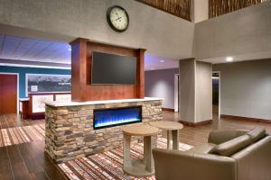 Hampton Inn & Suites Pocatello في بوكاتيلو: غرفة معيشة بها موقد وساعة على الحائط