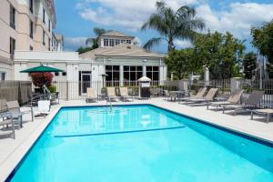 a swimming pool with chairs and a building at Hilton Garden Inn Arcadia/Pasadena Area in Arcadia