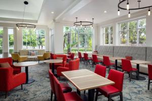 a restaurant with tables and chairs and windows at Hilton Garden Inn Arcadia/Pasadena Area in Arcadia