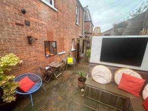 a patio with a tv and chairs and a brick building at The Green House Hythe in Kent