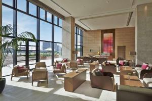 eine Lobby mit Stühlen, Tischen und Fenstern in der Unterkunft Hilton Okinawa Chatan Resort in Chatan