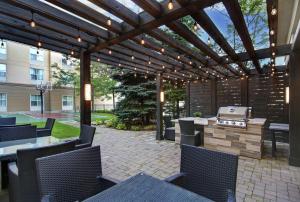 un patio con parrilla, mesas y sillas en Homewood Suites by Hilton Burlington en Burlington