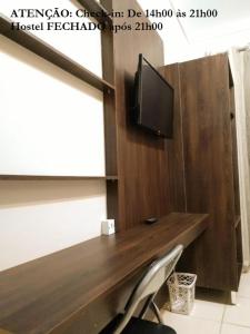 a wooden desk with a tv and a chair at Elô Hostel in Brasilia