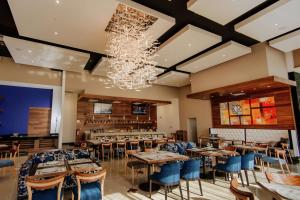 ein Restaurant mit Tischen, Stühlen und einem Kronleuchter in der Unterkunft Hilton Garden Inn Puebla Angelopolis in Puebla