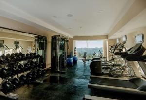 une salle de sport avec une rangée de tapis de course et de machines dans l'établissement Hilton Garden Inn Puebla Angelopolis, à Puebla