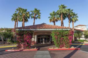 ランチョ・ミラージュにあるHilton Garden Inn Palm Springs/Rancho Mirageのピンクの花とヤシの木がある建物