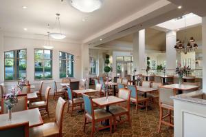 um restaurante com mesas, cadeiras e janelas em Hilton Garden Inn Palm Springs/Rancho Mirage em Rancho Mirage
