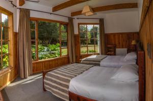 two beds in a room with windows at Andes Lodge, Puelo Patagonia in Puelo