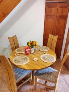 a wooden table with plates and glasses and flowers on it at Bryn Mynach Annex in Barmouth