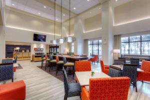 ein Restaurant mit Tischen und Stühlen und eine Bar in der Unterkunft Hampton Inn & Suites Dallas/Plano-East in Plano
