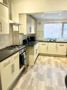 eine Küche mit weißen Schränken und schwarzen Arbeitsplatten in der Unterkunft Convenient & Modern Private Bedroom Space near Barnsley Hospital in Barnsley