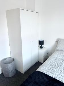 ein Schlafzimmer mit einem großen weißen Schrank neben einem Bett in der Unterkunft Convenient & Modern Private Bedroom Space near Barnsley Hospital in Barnsley