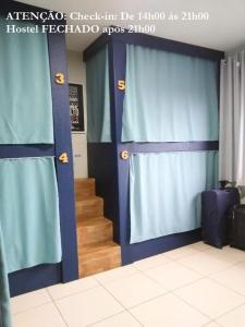 Habitación con cortinas azules y escalera con escaleras. en Elô Hostel en Brasilia