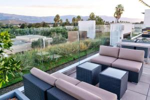 eine Terrasse mit einem Sofa und Stühlen auf dem Balkon in der Unterkunft Hilton Garden Inn Santa Barbara/Goleta in Santa Barbara