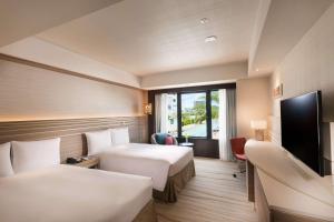 a hotel room with two beds and a flat screen tv at DoubleTree by Hilton Okinawa Chatan Resort in Chatan