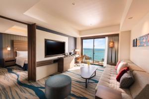 a hotel room with a couch and a television at DoubleTree by Hilton Okinawa Chatan Resort in Chatan