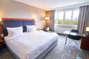 una camera d'albergo con un grande letto e una scrivania di Radisson Blu Hotel Dortmund a Dortmund