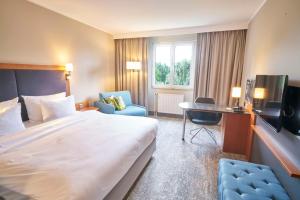 a hotel room with a large bed and a desk at Radisson Blu Hotel Dortmund in Dortmund