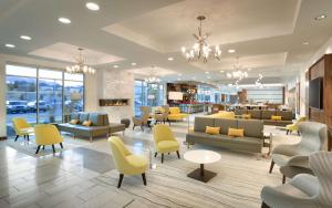 a lobby with yellow chairs and couches and tables at Hilton Garden Inn Lehi in Lehi