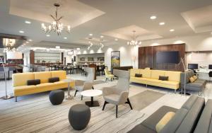 un hall avec des canapés jaunes, des tables et des chaises dans l'établissement Hilton Garden Inn Lehi, à Lehi
